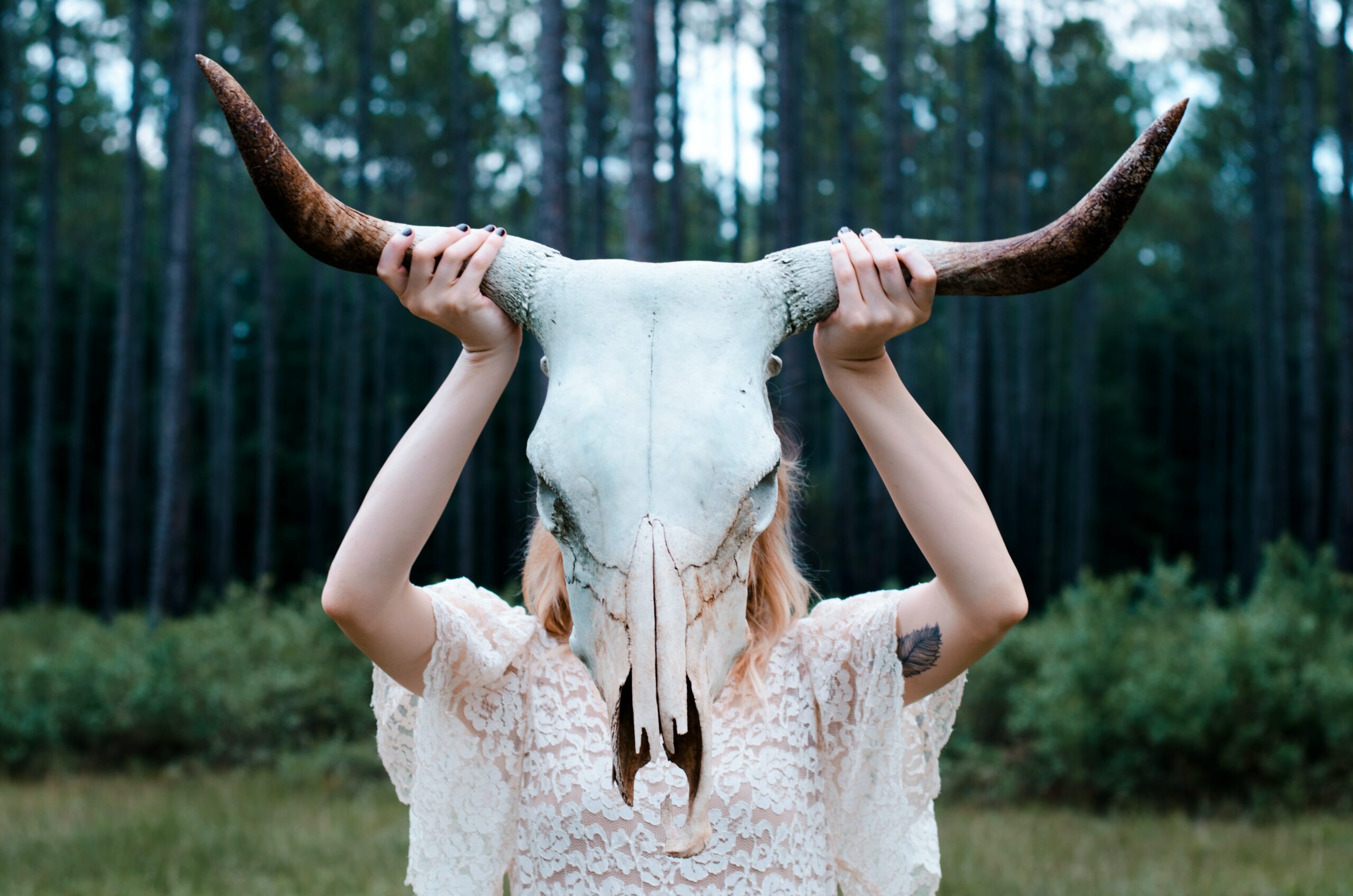 A woman holding up a skull with horns.